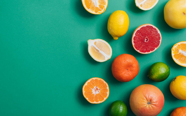 Cítricos sobre mesa verde con espacio para copiar. Cítricos frescos incluyendo lima, limones, naranja, pomelo amarillo, pomelo rosa y mandarinas sobre fondo verde con espacio vacío - Foto, Imagen