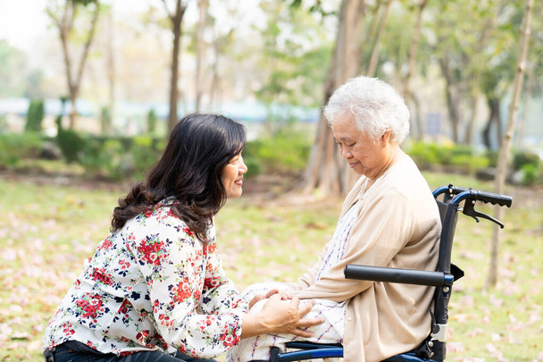 Azjatycka starsza lub starsza pani pacjentka z opieki, pomocy i wsparcia szczęśliwy na wózku inwalidzkim w parku w wakacje, zdrowe silnej koncepcji medycznej. - Zdjęcie, obraz