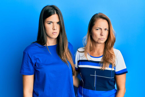 Latino perheen äiti ja tytär yllään rento vaatteita yli sininen tausta skeptinen ja hermostunut, murjottaa järkyttynyt ongelman vuoksi. negatiivinen henkilö.  - Valokuva, kuva