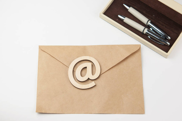 Een envelop met pen en houten bordje E-mail ligt op een witte achtergrond. Concept e-mail bericht brief. Bovenaanzicht - Foto, afbeelding