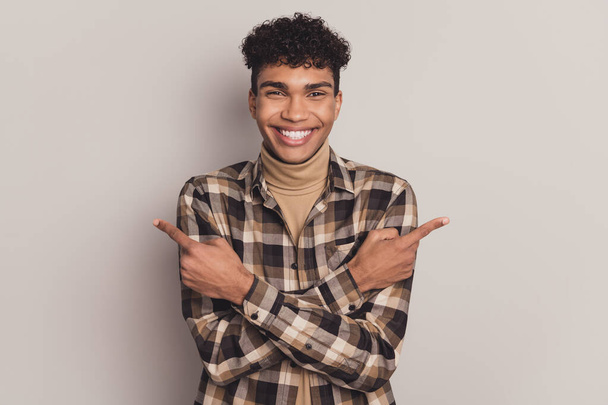 Photo of positive guy direct fingers empty space wear plaid shirt turtleneck isolated grey color background - Foto, immagini