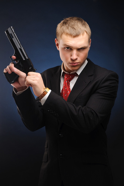 Young man with pistol over dark background - Foto, imagen