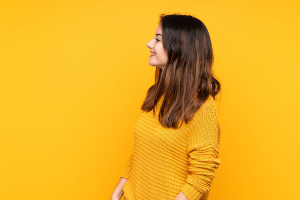 Young caucasian woman isolated on yellow background laughing in lateral position - Φωτογραφία, εικόνα