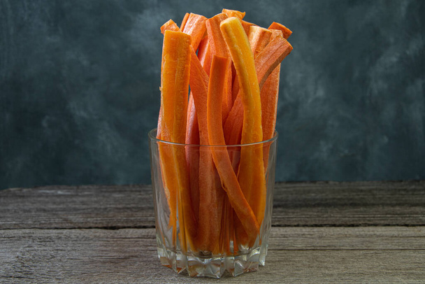 Καρότο κολλάει σε γυαλί σε ξύλινο τραπέζι. Φυτικές τροφές για χορτοφάγους. Ενισχυμένη δίαιτα χαμηλών θερμίδων από γεωργικά προϊόντα - Φωτογραφία, εικόνα