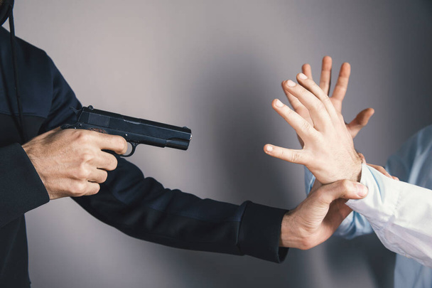 Ein Mann hält eine schwarze Pistole in der Hand, bedroht - Foto, Bild