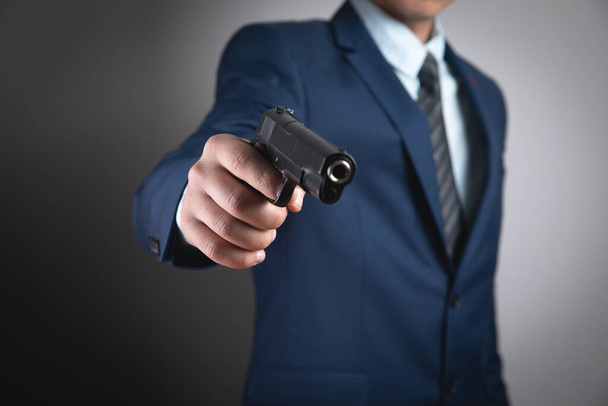 un hombre sosteniendo una pistola negra en su mano amenazando - Foto, Imagen