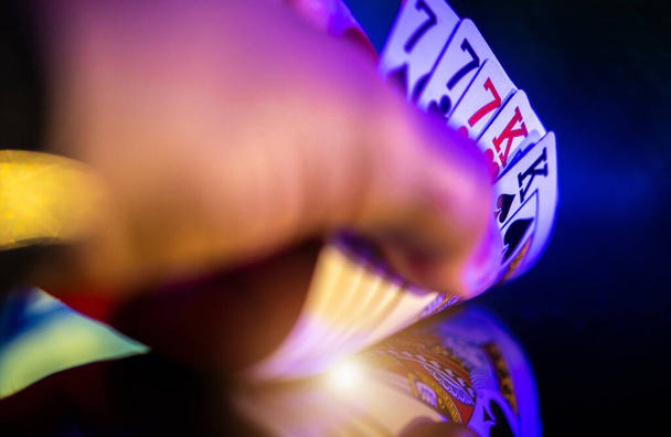 Poker Player Looking on His Cards. Full House in Hands of the Player Close Up. Glassy Dark Table with Reflections. Casino Gambling and Entertainment Theme. - 写真・画像