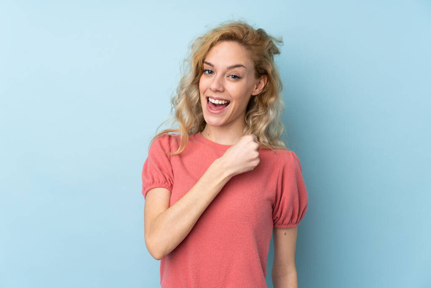 Young blonde woman isolated on blue background celebrating a victory - Foto, Bild