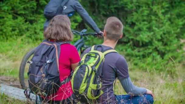 Túrázók ülni és pihenni, nézni két kerékpárosok lovagolni múlt erdőben, HANDHELD - Felvétel, videó