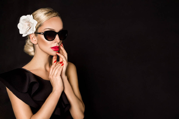 Sunglasses fashion. Portrait of beautiful elegant woman in fashionable sunglasses with perfect makeup and red lips and nails on black background in studio. Elegance. - Fotó, kép