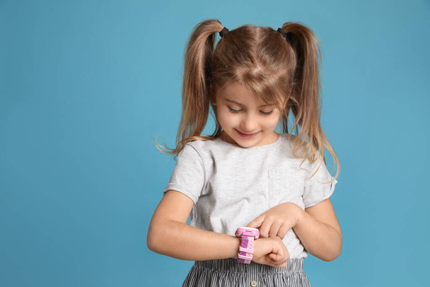 Little girl with smart watch on light blue background, space for text - 写真・画像