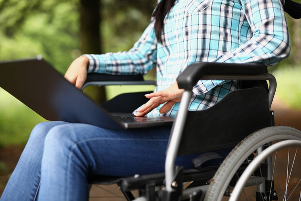 Femme en fauteuil roulant sur ses genoux avec ordinateur portable - Photo, image