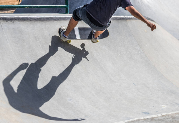 A skater going up a ramp in the skatepark - young skater about to fall - 写真・画像