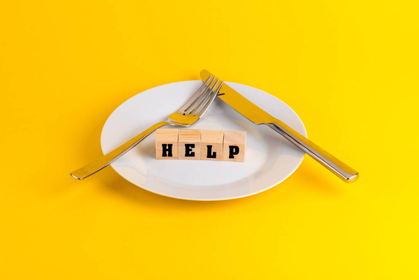 The word HELP on wooden blocks on an empty plate with a knife and fork - Photo, image