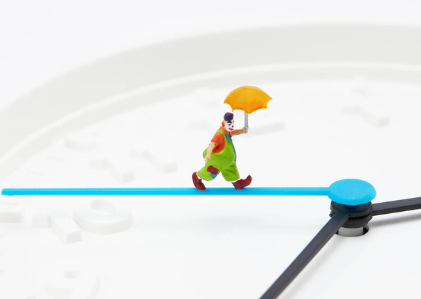 A closeup shot of clown holding umbrella figurine minute clock isolated on white background - Photo, Image