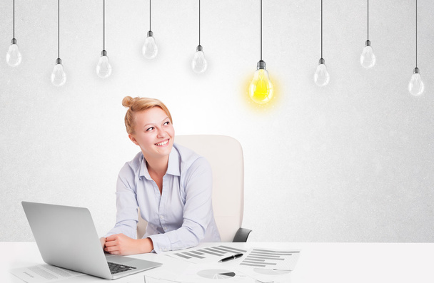 Business woman sitting at table with idea light bulbs - Zdjęcie, obraz