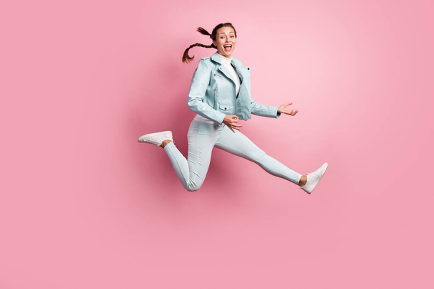 Full length photo portrait of excited girl playing imaginary guitar jumping up isolated on pastel pink colored background - Photo, image