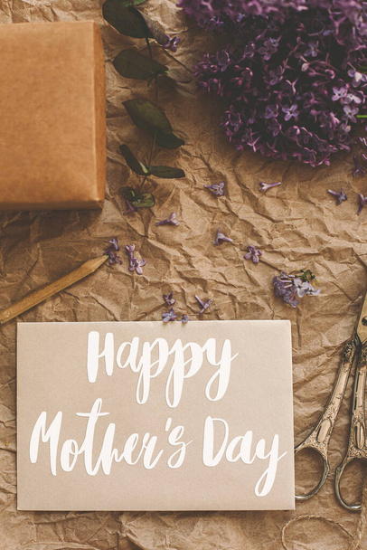 Happy mother's day. Happy mother's day text on card and lilac flowers, gift, pencil, vintage scissors on rustic background. Stylish floral greeting card. Handwritten lettering. Mothers day - Photo, Image
