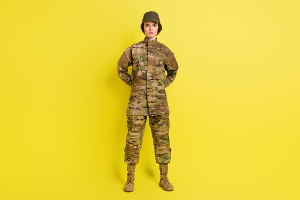 Full size photo of concentrated young girl standing arms behind back isolated on yellow color background - Foto, Bild
