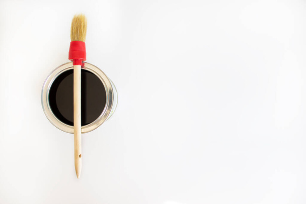 Paint symbol. A round paint brush lies on a can of paint on a white background. Copy space. Business and paint concept. - Fotó, kép