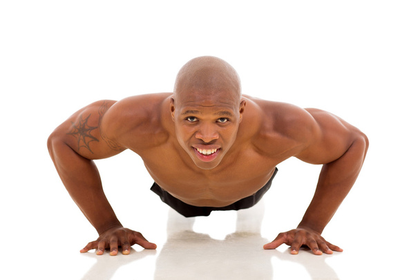 young African man doing pushups on floor - 写真・画像