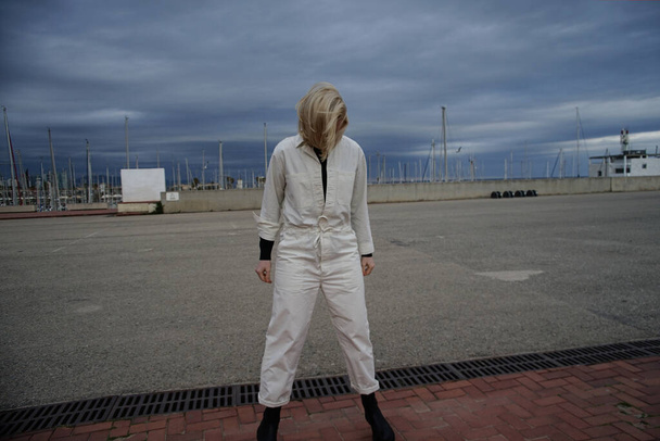 Blonde woman wearing white jumpsuit posing outdoor. - Φωτογραφία, εικόνα