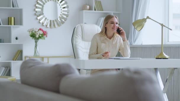 Nuori nainen puhuu puhelimessa kotona toimistossa - Materiaali, video