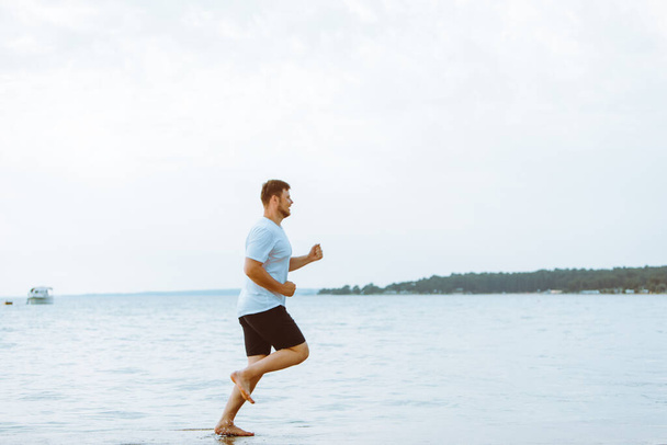 man running by sea beach barefoot copy space - 写真・画像