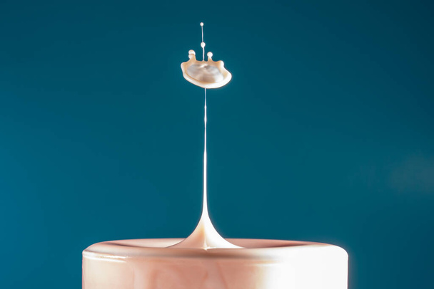Две капли молока падают в длинный стакан для питья ударяясь друг о друга затем жидкая поверхность имеет форму гриба - Фото, изображение