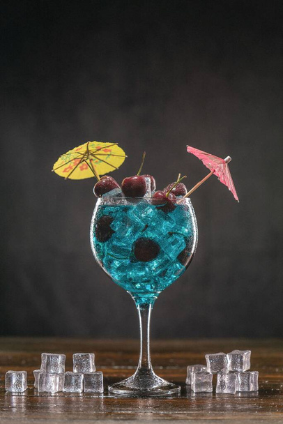 Blue cocktail in a glass with ice and cherry - Foto, imagen