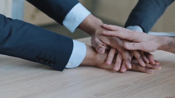 Closeup arms of multinational multiracial group company of different ethnicity people colleagues business men managers office workers stack hands put palms together on wooden table, team trust support - Footage, Video