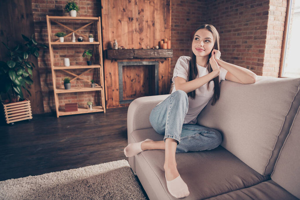 Photo of pretty thoughtful young woman white t-shirt sitting couch having rest smiling indoors apartment room - Foto, immagini