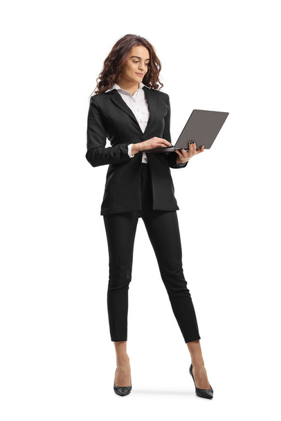 Full length portrait of a young businesswoman holding a laptop computer isolated on white background - Foto, Bild