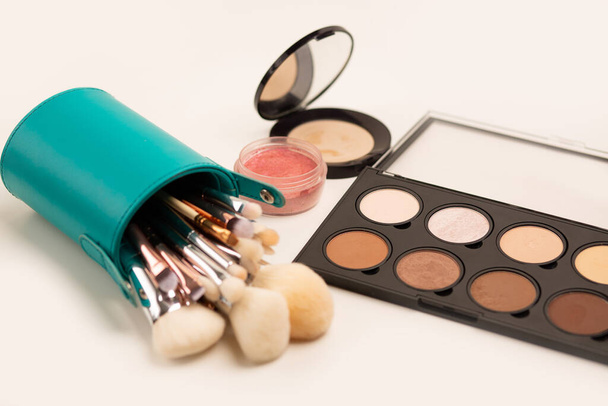 Juego de maquillaje: kit de pinceles en estuche, paleta de iluminadores y bronceadores y rubor sobre fondo gris - Foto, Imagen