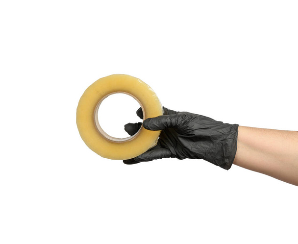 female hand in black latex glove holds roll of transparent  tape, white isolated background - Photo, Image