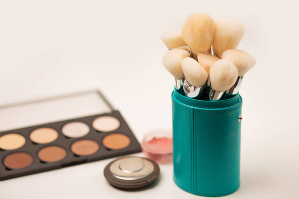 Bir çantada yüz makyajı için fırça seti, palet hatları ve gri arka planda bastırılmış toz - Fotoğraf, Görsel