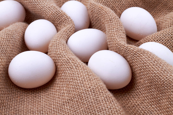 Kahverengi bir kumaş üzerinde beyaz yumurtalar.. - Fotoğraf, Görsel