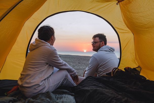 coppia seduta in tenda da campeggio guardando il tramonto. solidità; - Foto, immagini