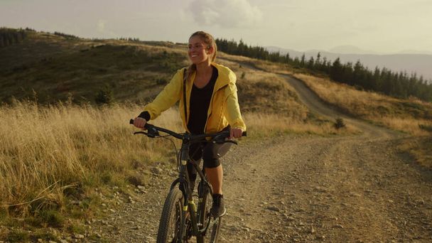Rider cycling on sport bike in mountains. Smiling woman riding mountain bike  - Photo, Image