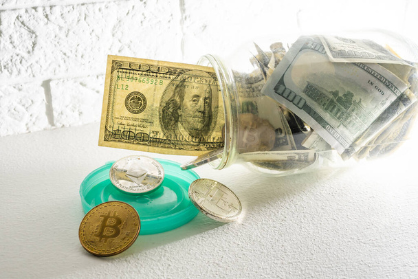 Bitcoins brązowa złota moneta w szklanym słoiku na białym drewnianym stole. Zestaw kryptowalut z prawdziwym euro, dolary w słoiku. Oszczędności, inwestycje, koncepcja ryzyka finansowego - Zdjęcie, obraz