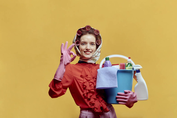 A cleaning lady with cleaning tools makes an OK gesture. Pin-up style. - Foto, afbeelding