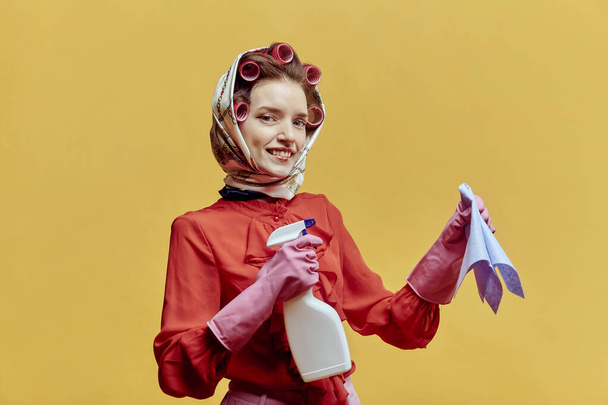 Happy cleaning lady wearing hair curlers and a headscarf. Pin-up style. - 写真・画像