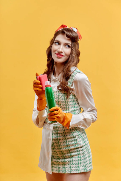 A young female cleaner holds tools for cleaning the house. Pin-up style. - Φωτογραφία, εικόνα