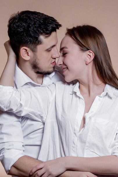 Couple in love looking at each other with love and smiling on brown background. Attractive people, closeup portrait. Studio shot, commercial, advertising concept. - Foto, Imagem