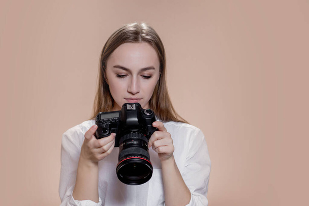 Close up portrait of woman photographer with camera taking pictures with digital camera on brown background. - Fotó, kép