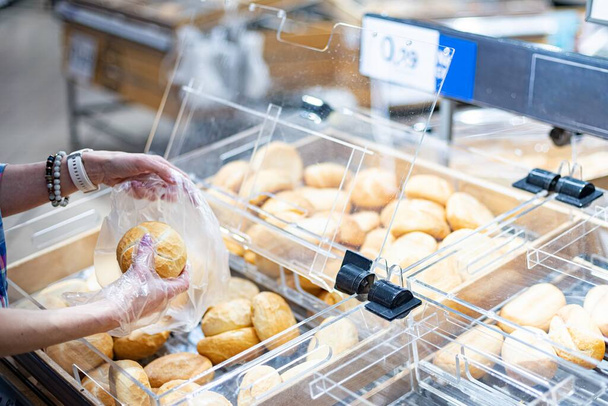 Κοντινό χέρι γυναικών επιλέγοντας ψωμί και ρολά στο σούπερ μάρκετ - Φωτογραφία, εικόνα