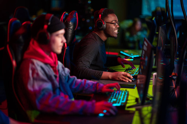 International gaming event. Arena for conducting esports competitions. Young players with headphones are playing a popular online game. - Photo, Image