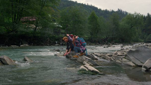 Mies ja nainen istuvat kivellä joella. Pari roiskeita vettä ilmassa  - Valokuva, kuva