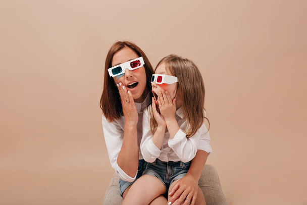  Close up portrait of pretty woman with dark hair wearing movie glasses watching movie with her little adorable girl. High quality photo - Photo, Image