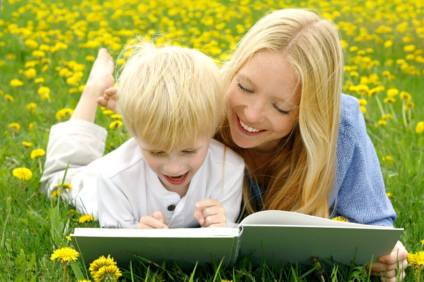 Madre y niño feliz lectura libro fuera en la pradera
 - Foto, imagen